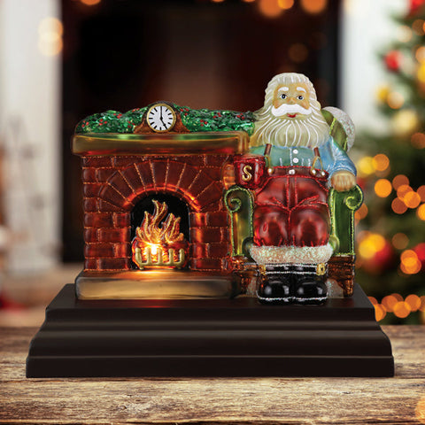 Old World Christmas Santa at Hearth Light displayed beside a glowing fireplace in a festive room