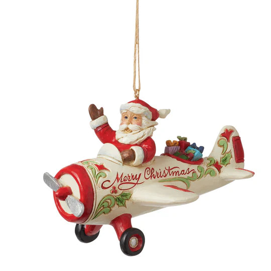 Jim Shore ornament featuring Santa waving from a cream and red airplane with holly accents, gifts in the back, and Merry Christmas written on the side. Front View