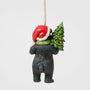 Back view of Jim Shore Lodge Black Bear Ornament showing the bear in a Santa hat carrying a decorated Christmas tree over its shoulder.