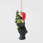Side view of Jim Shore Lodge Black Bear Ornament showing the bear carrying a decorated tree with gold garland and wearing a Santa hat.