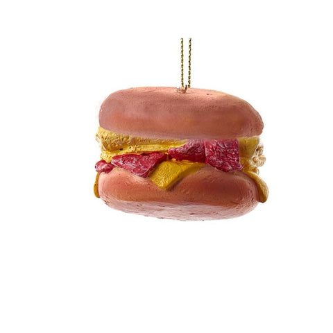 Breakfast sandwich ornament with a round bun, bacon strips, egg, and melted cheese hanging from a gold cord.