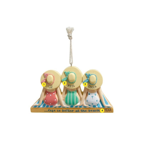 Personalized ornament of three women sitting on striped beach towels in colorful swimsuits and sun hats, with beach wording on the front and room for names and year.