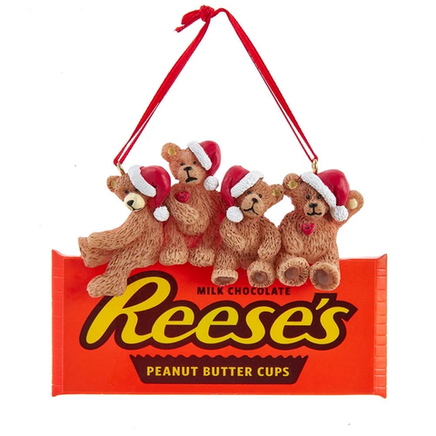 Ornament featuring four teddy bears in Santa hats sitting on a Reese’s Peanut Butter Cups wrapper with a red hanging ribbon.