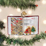 Ornament shaped like an open book with cookie illustrations on a Christmas tree.
