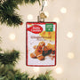 Betty Crocker Gingerbread cookie mix ornament hanging on a Christmas tree with lights in the background.