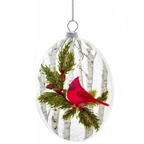 Glass disc ornament featuring a single red cardinal perched among evergreen branches with white birch trees in the background.