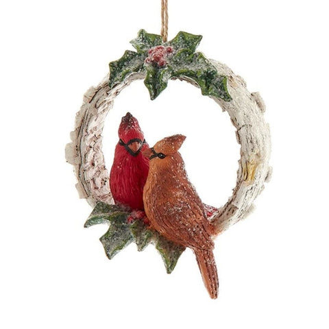 Birch-style wreath ornament with holly leaves and red berries, featuring a pair of cardinals perched together inside the ring.