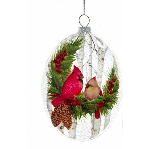Glass disc ornament featuring two red cardinals among evergreen branches, red berries, pinecones, and white birch trees.