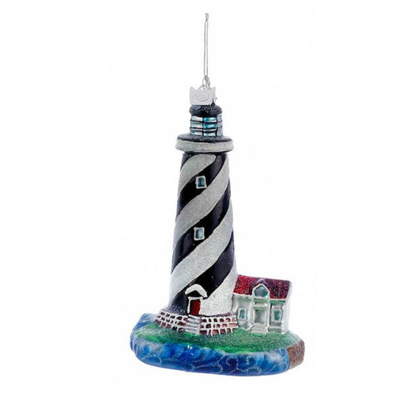 Black and white striped lighthouse ornament with spiral tower design, small coastal cottage, ocean wave base, and silver hanging cord.