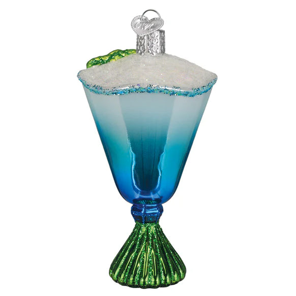 Decorative glass ornament resembling a blue cocktail with green rim and white foam on a white background