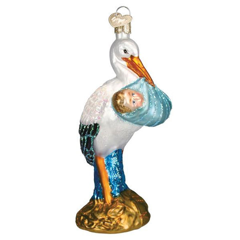 Decorative glass stork holding a baby in a blue blanket on a white background