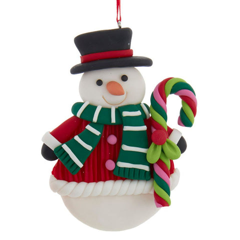 Snowman ornament wearing a red outfit, green striped scarf, and black top hat while holding a colorful twisted candy cane.