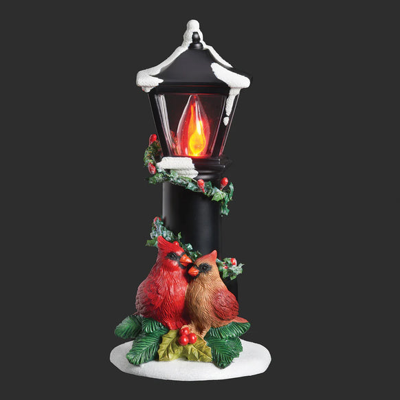 Cardinals Nestled Under a Flickering Flame Lamppost Night-Light with two birds resting beneath a snowy black lamppost wrapped in holly and berries