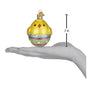 Decorative chick ornament in an egg with a hand holding it for scale on a white background