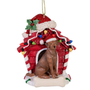 Chocolate Labrador Retriever wearing a Santa hat in a red dog house Christmas ornament decorated with colorful lights.