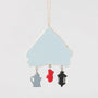 Back view of Jim Shore Christmas at the Lodge Ornament showing the light blue reverse side and dangling charms shaped like a coffee pot, mitten, and lantern.