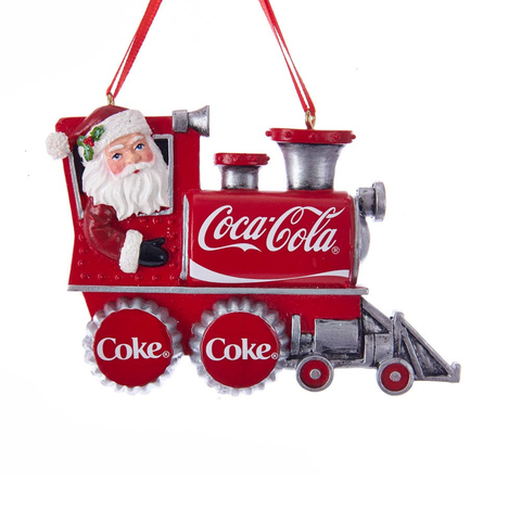 A Coca-Cola Christmas ornament shaped like a train, featuring a red body with silver details, a portrait of Santa Claus in the cab, and Coca-Cola branding on the side and wheels, hanging against a white background.
