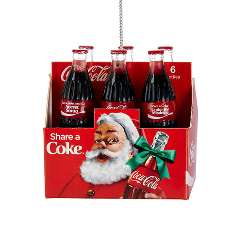 Coca-Cola six-pack carton ornament with six glass-style bottles, red packaging, Santa artwork, and holiday-themed Coke bottle labels.