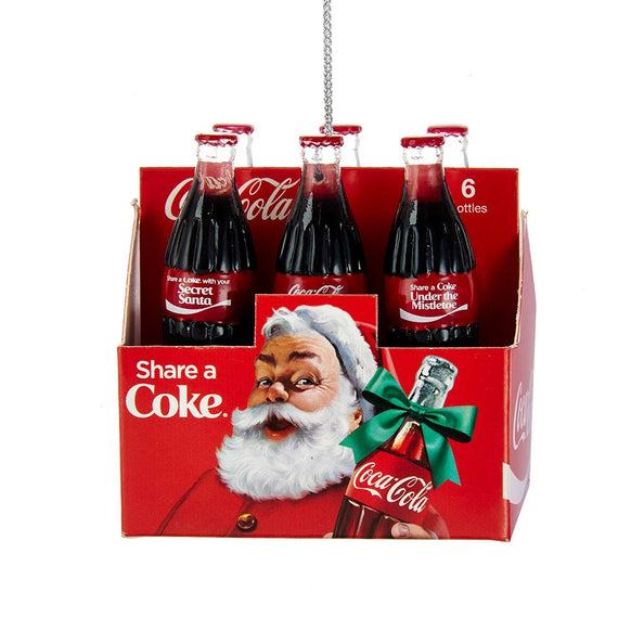Coca-Cola six-pack carton ornament with six glass-style bottles, red packaging, Santa artwork, and holiday-themed Coke bottle labels.