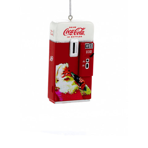 Coca-Cola vending machine ornament in red and white with vintage-style detailing, Coca-Cola logo, coin slot, and Santa holding a bottle on the front.