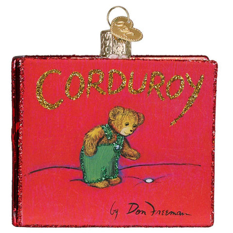 Decorative ornament shaped like a book titled 'Corduroy' with a teddy bear illustration on a red background.