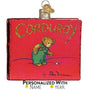 Decorative ornament shaped like a book titled 'Corduroy' with a teddy bear illustration on a red background.