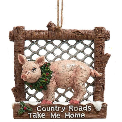 Pig ornament in a rustic fence-style frame wearing a holly wreath, with the phrase “Country Roads Take Me Home” on the bottom.