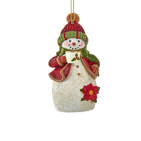 Snowman ornament wearing a red knit hat, red coat, and green scarf while holding a festive mug with holly detail and glittered accents.