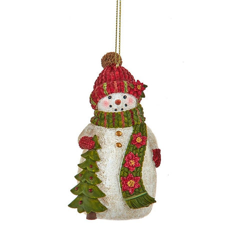 Snowman ornament wearing a red knit hat and green scarf with poinsettia accents while holding a decorated Christmas tree.