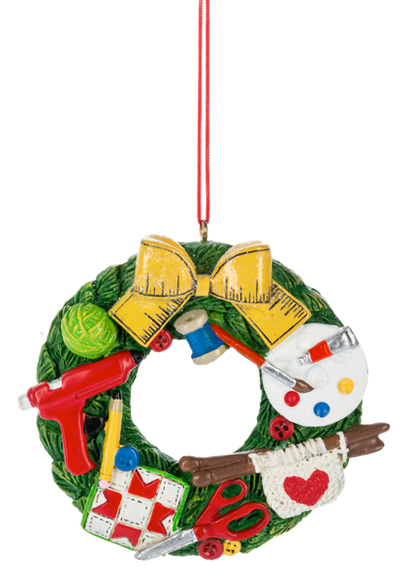 Craft wreath ornament featuring sewing and crafting supplies including scissors, thread, yarn, paint, a glue gun, quilt squares, and knitting needles.