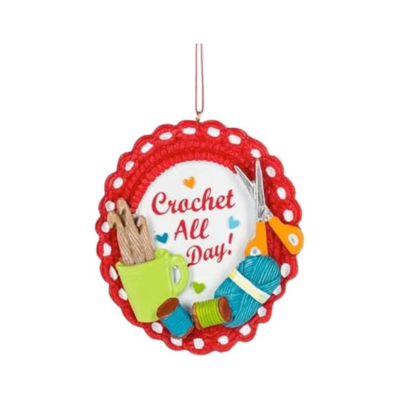 Crochet All Day ornament with a red crocheted-look border, crochet hooks in a green mug, blue yarn, thread spools, and scissors.