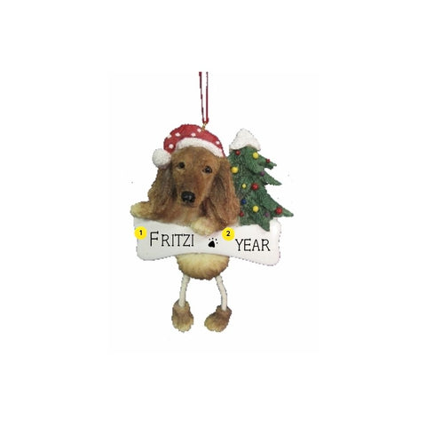 Personalized longhaired dachshund ornament with a dog in a Santa hat beside a Christmas tree and space for a name and year on the white banner.