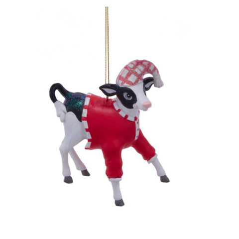Black and white dairy cow ornament wearing a red pajama outfit and matching plaid nightcap, posed mid-step with a cheerful expression.