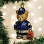 Teddy bear ornament in EMT uniform hanging on a Christmas tree with lights in the background