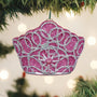 Pink and silver glittery ornament hanging on a Christmas tree with blurred lights in the background.