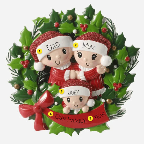 Christmas ornament with three people in red outfits on a holly wreath