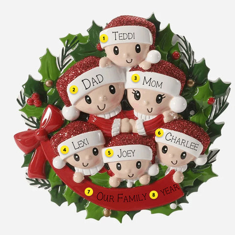 Christmas ornament with six family members in Santa hats on a green wreath with red ribbon.