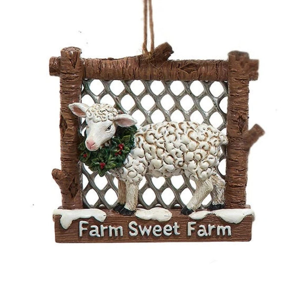 Sheep ornament in a rustic fence-style frame wearing a holly wreath, with the phrase “Farm Sweet Farm” on the bottom.