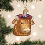 Cow-shaped Christmas ornament with floral crown on a decorated tree