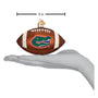 Decorative football ornament with a Florida Gators logo, held in a hand to show size, on a white background.