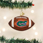 Football-shaped ornament with a Florida Gators logo, hanging on a Christmas tree.