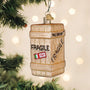 Decorative Christmas ornament shaped like a shipping crate with 'Fragile' label, hanging on a tree.