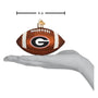 Football-shaped ornament with a Georgia logo, held in a hand for scale, on a white background.