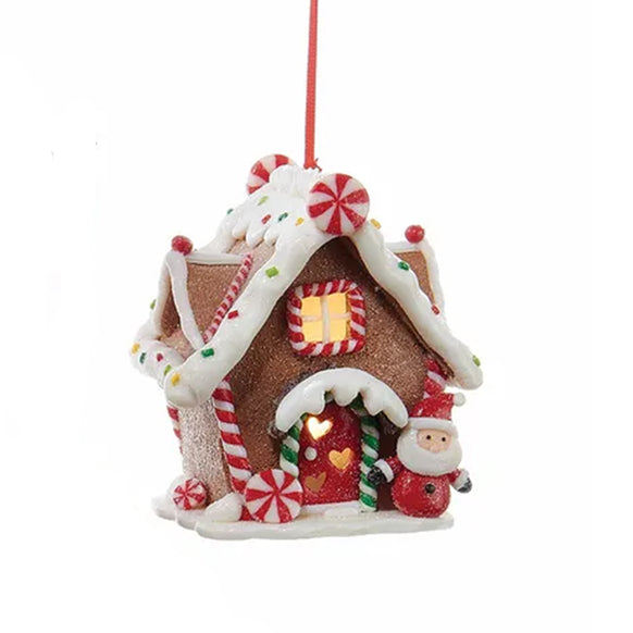 Decorative gingerbread house ornament with candy cane details on a white background