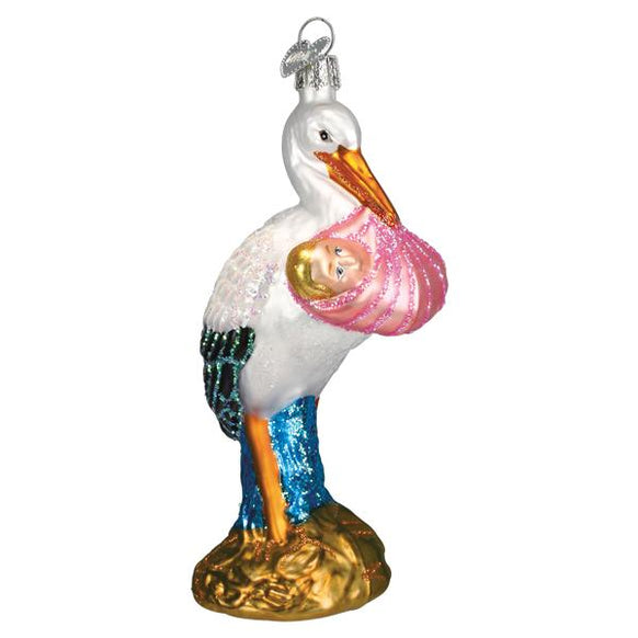 Decorative stork ornament holding a baby in a pink blanket on a white background