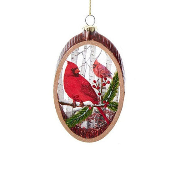 Christmas ornament with red cardinals on a branch against a snowy background