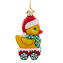 Side view of glass duck ornament featuring a yellow duck in a Santa hat, green scarf, red cart, and white snowflake wheels.