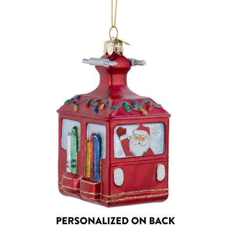 Personalized glass ski gondola ornament with Santa waving from a red gondola, colorful skis on the side, and text noting personalization on back.