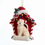 Cream Goldendoodle wearing a Santa hat in a red dog house Christmas ornament decorated with colorful lights.