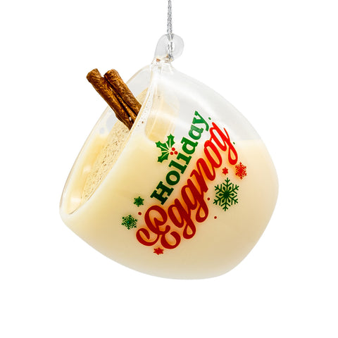 Glass eggnog ornament with creamy white fill, cinnamon stick detail, and “Holiday Eggnog” wording in red and green with snowflake accents.